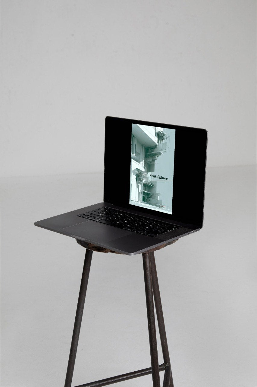 A black laptop sits open on a tall black metal stool against a plain light gray studio background. The laptop screen displays a grayscale architectural photograph with the text 'Modern Systems'.